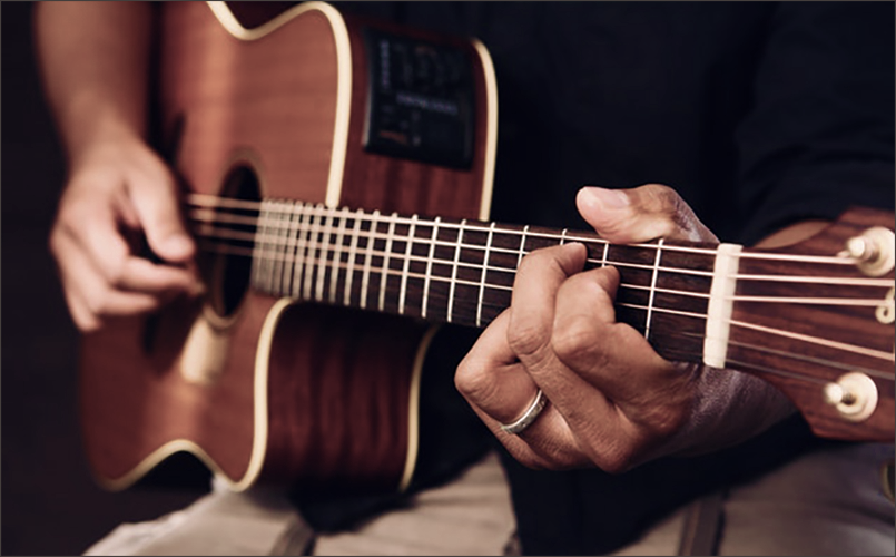 Gros plan d'une guitare avec deux mains qui jouent de cet instrument